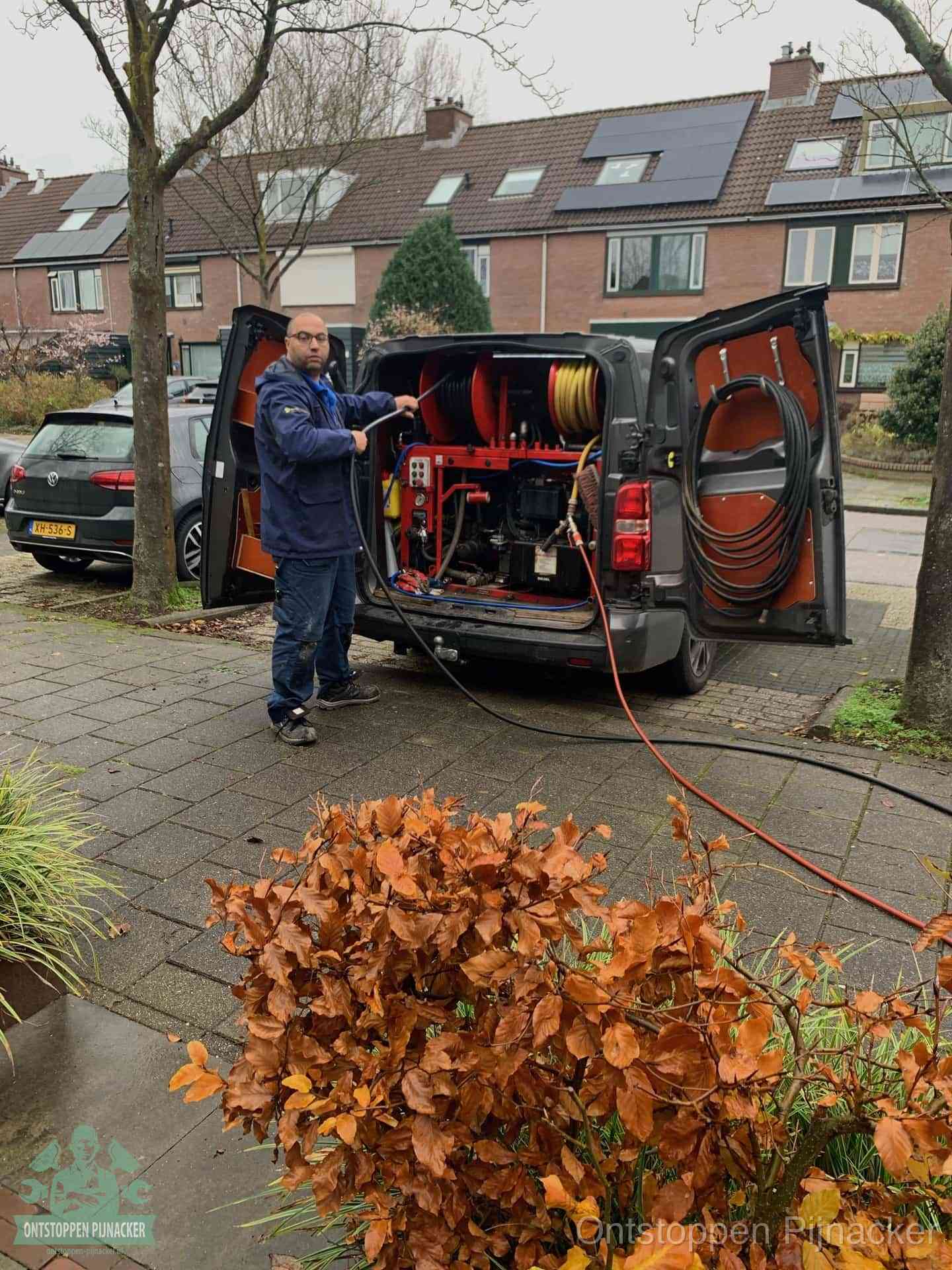 Monteur met rioolreinigingsbus levert rioolservice in de wijk in Pijnacker