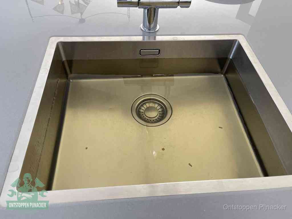 Stilstaand water in een rvs spoelbak dat niet wegloopt, een duidelijk signaal van een gootsteenverstopping in Pijnacker