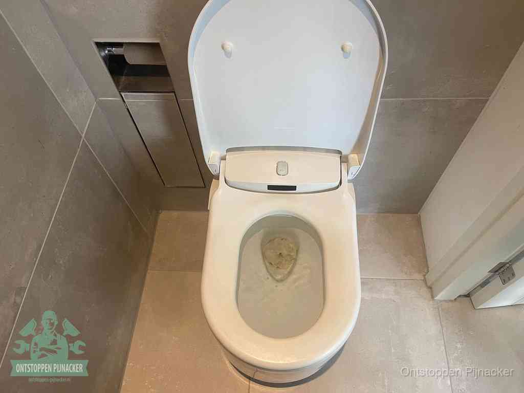 Een wit hangtoilet waarin een prop wc-papier op het water blijft drijven, een duidelijk signaal van een verstopte wc in Pijnacker