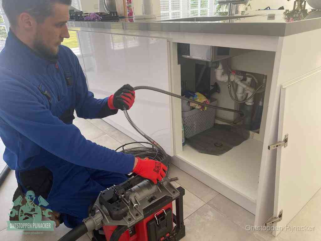 Een monteur reinigt de keukenafvoer grondig met een veermachine om terugkerende gootsteenverstoppingen te voorkomen in Pijnacker